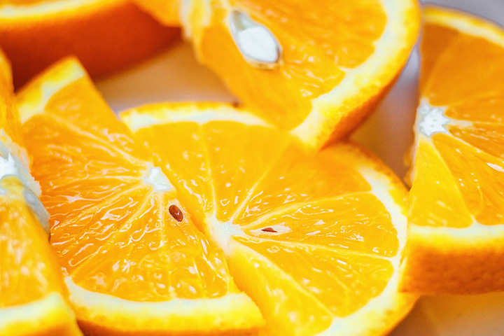 Natural Pharmaceuticals CalciumControl™ Lähedalt pildistatud mahlased oranži viilud, kus on nähtavad seemned ja tsitruselise fookus.